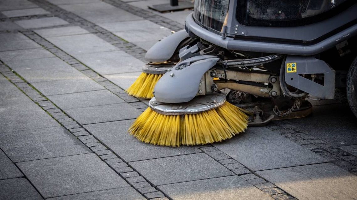 Imagen de una barredora vial en funcionamiento y haciendo su tarea de limpiar las calles